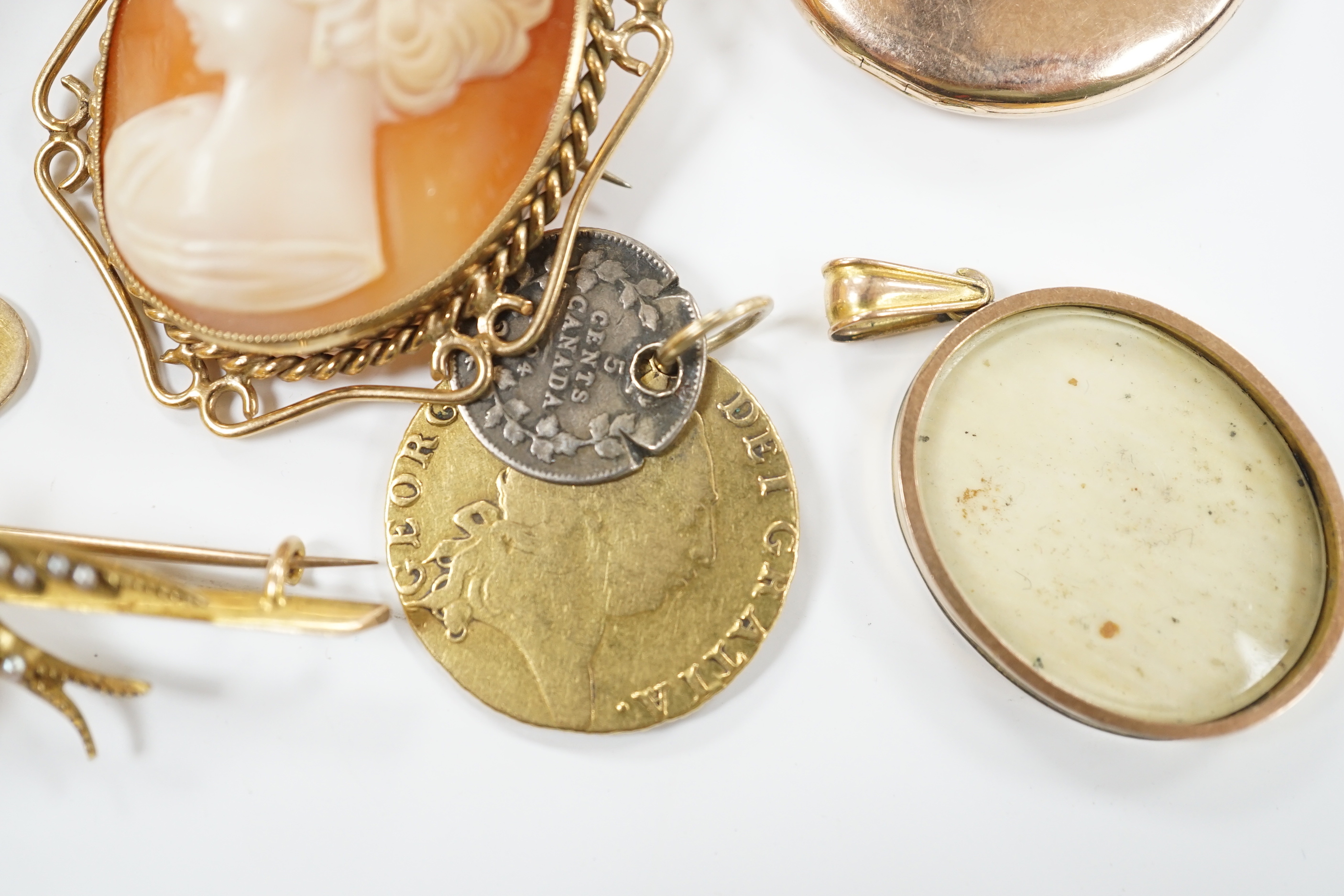 Assorted jewellery including a George III 1791 gold spade guinea (drilled), a modern 9ct gold mounted cameo shell brooch, an Edwardian 9ct gold oval locket, a pair of 9ct cufflinks, yellow metal and seed pearl set swallo